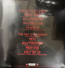The back cover of a vinyl record sleeve, wrapped in protective plastic. The cover is black with a list of remix tracks in red text, including 'The Day Is My Enemy' and 'Rebel Radio'.
