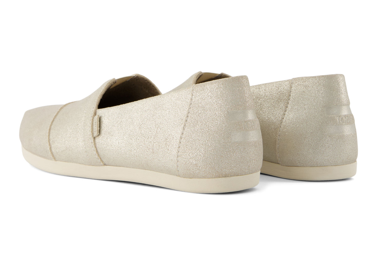 A women's Toms Alpargata slip-on shoe with a champagne metallic suede upper and a beige canvas footbed.