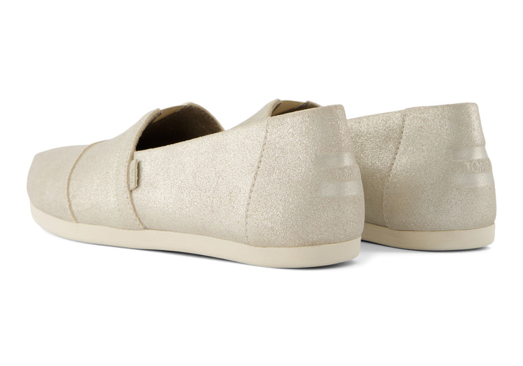 A women's Toms Alpargata slip-on shoe with a champagne metallic suede upper and a beige canvas footbed.