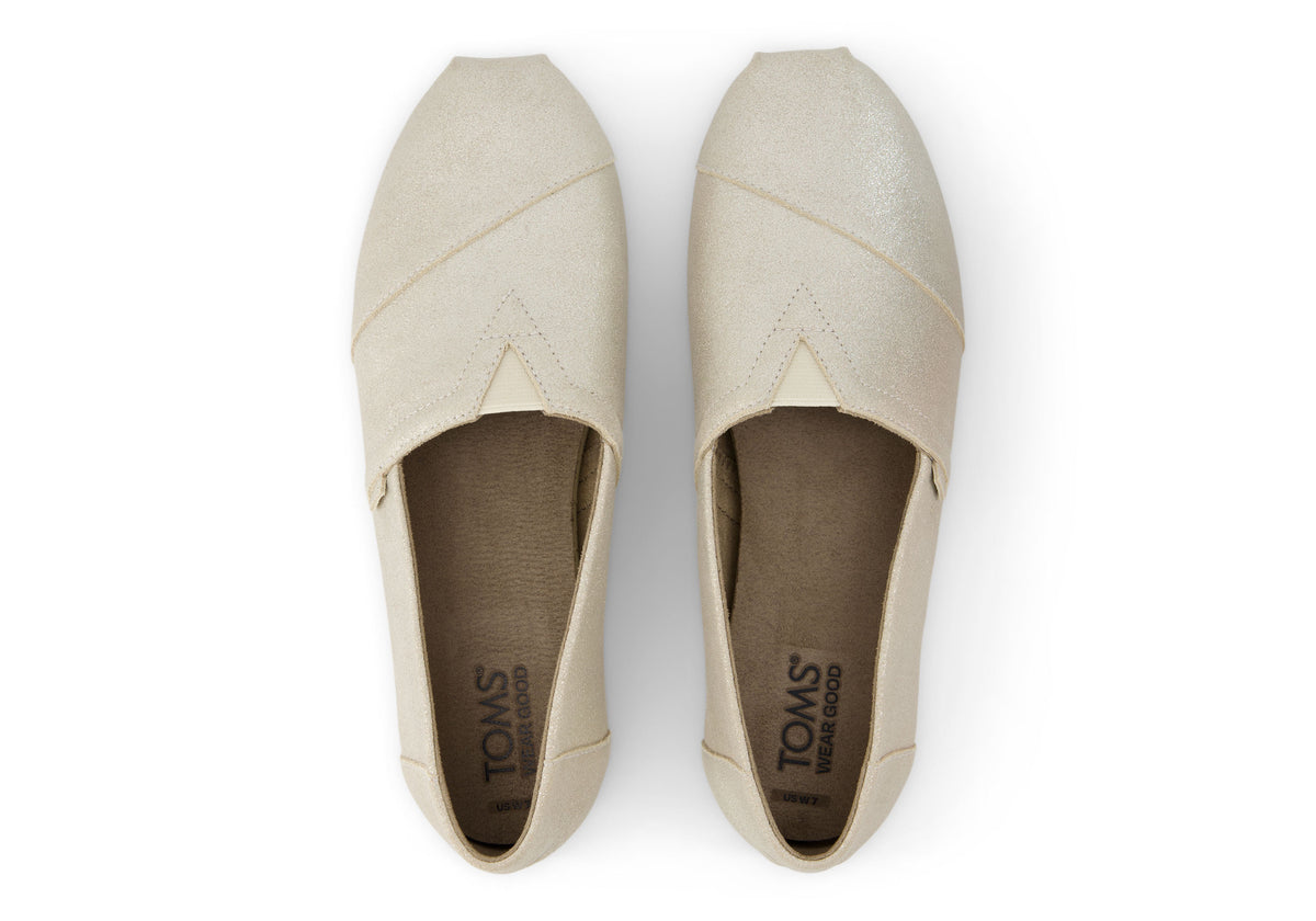 A women's Toms Alpargata slip-on shoe with a champagne metallic suede upper and a beige canvas footbed.