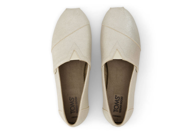 A women's Toms Alpargata slip-on shoe with a champagne metallic suede upper and a beige canvas footbed.