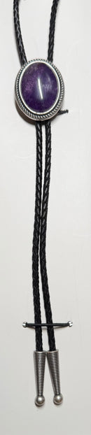 Bolo tie with purple stone and black leather cord on a white background
