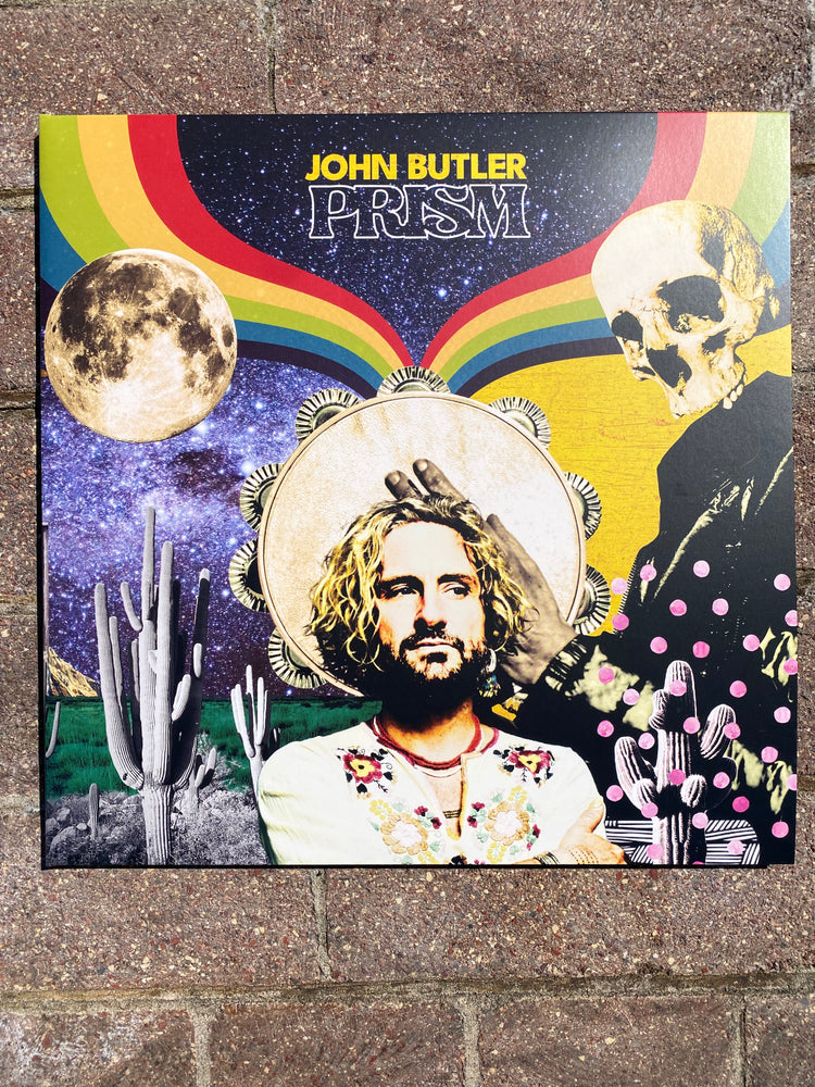 Album cover with colorful design featuring a face, rainbow, and space elements on a textured surface.