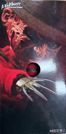 Mezco Toyz Freddy Krueger action figure with red sweater and glove, close-up view.