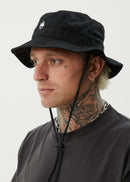 Man wearing a black bucket hat with the afends brand logo on a white background