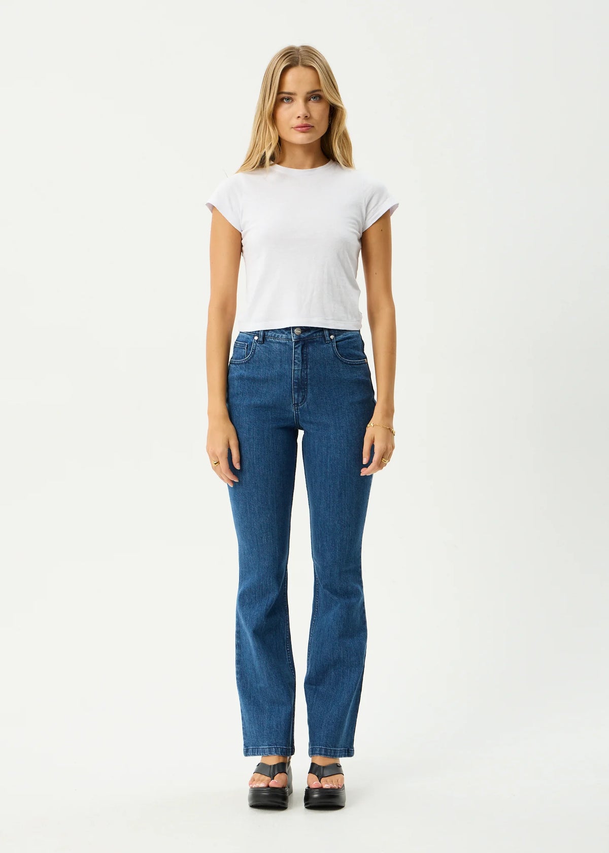 Woman wearing a white t-shirt and blue jeans on a white background