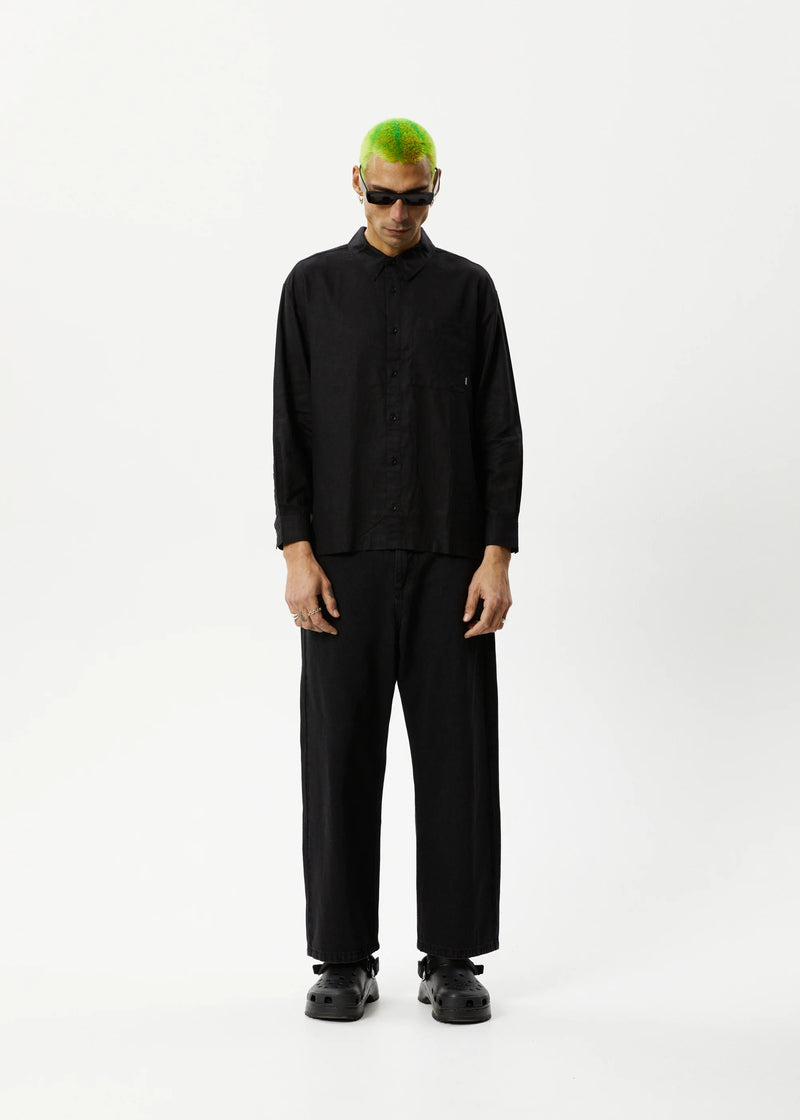 A male model wearing a long-sleeve black shirt with a traditional collar and button-up front, paired with black pants.