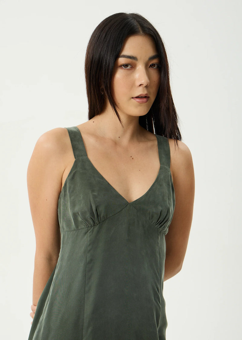 Woman wearing a green sleeveless top against a white background