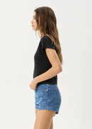 Woman wearing a black t-shirt and blue denim shorts on a white background