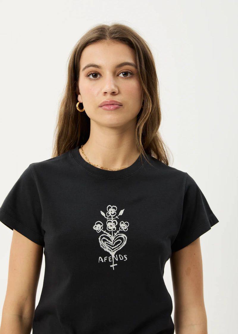 Person wearing a black t-shirt with a white floral design and 'AFREDS' text on a plain background