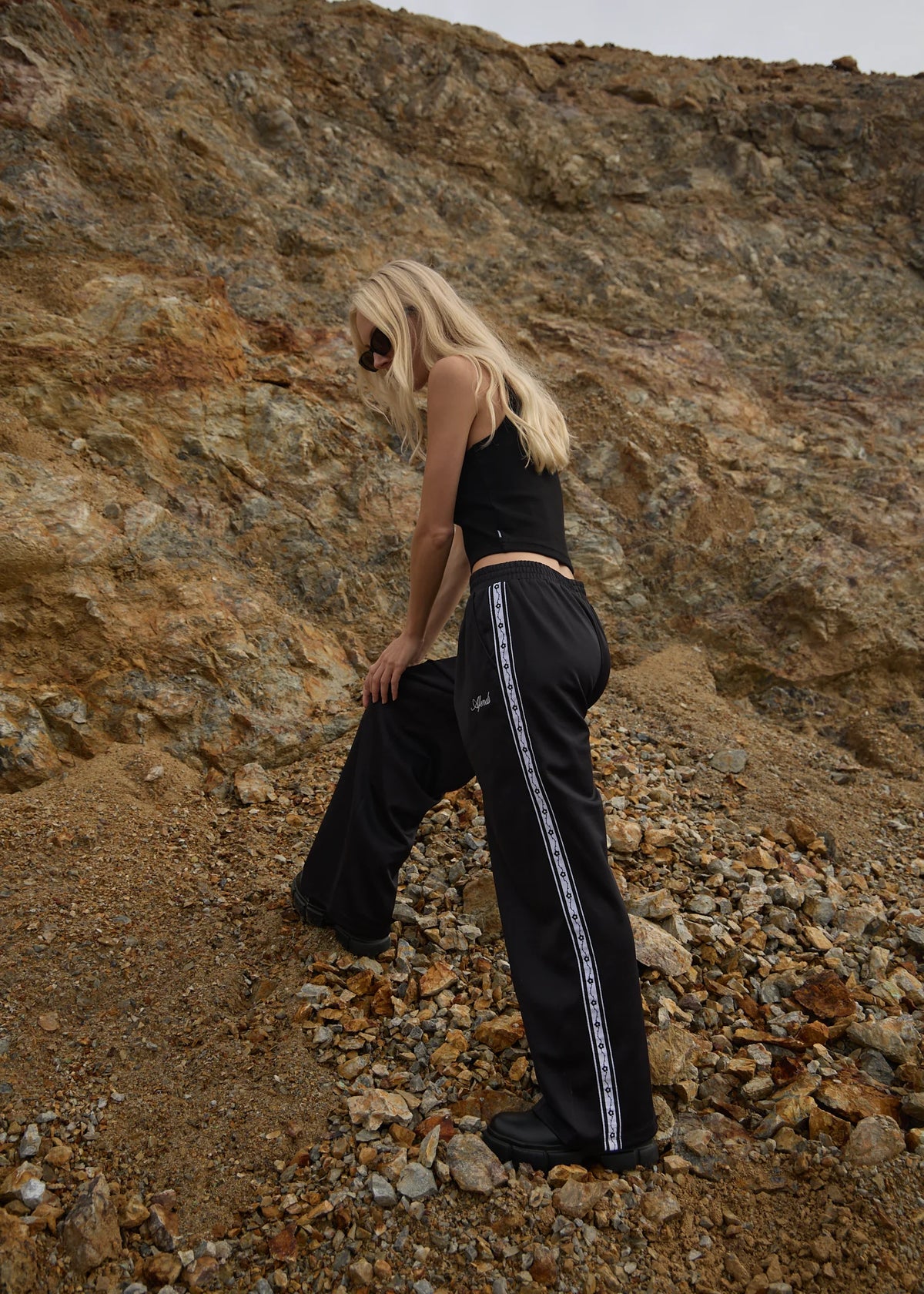 Person wearing a black outfit with white stripes on a rocky terrain