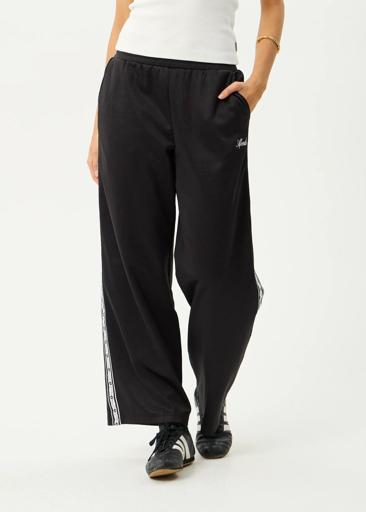 Black track pants with white stripes on a white background