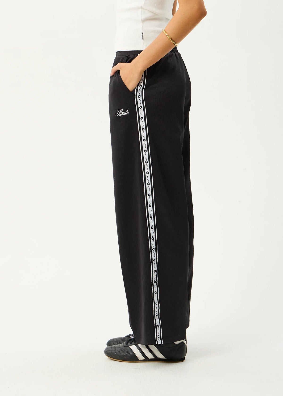Black track pants with white stripes on a white background
