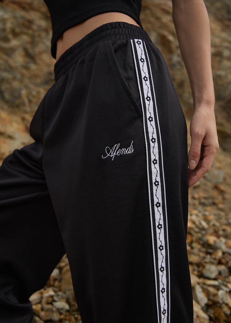 Black pants with a white stripe and 'Afends' branding against a rocky background