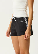 Black shorts with a white stripe and brand logo on a plain background