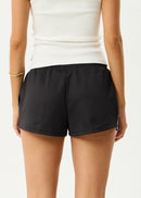 Person wearing black shorts and a white top on a plain background