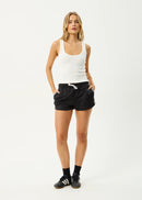 Woman wearing a white tank top and black shorts on a white background