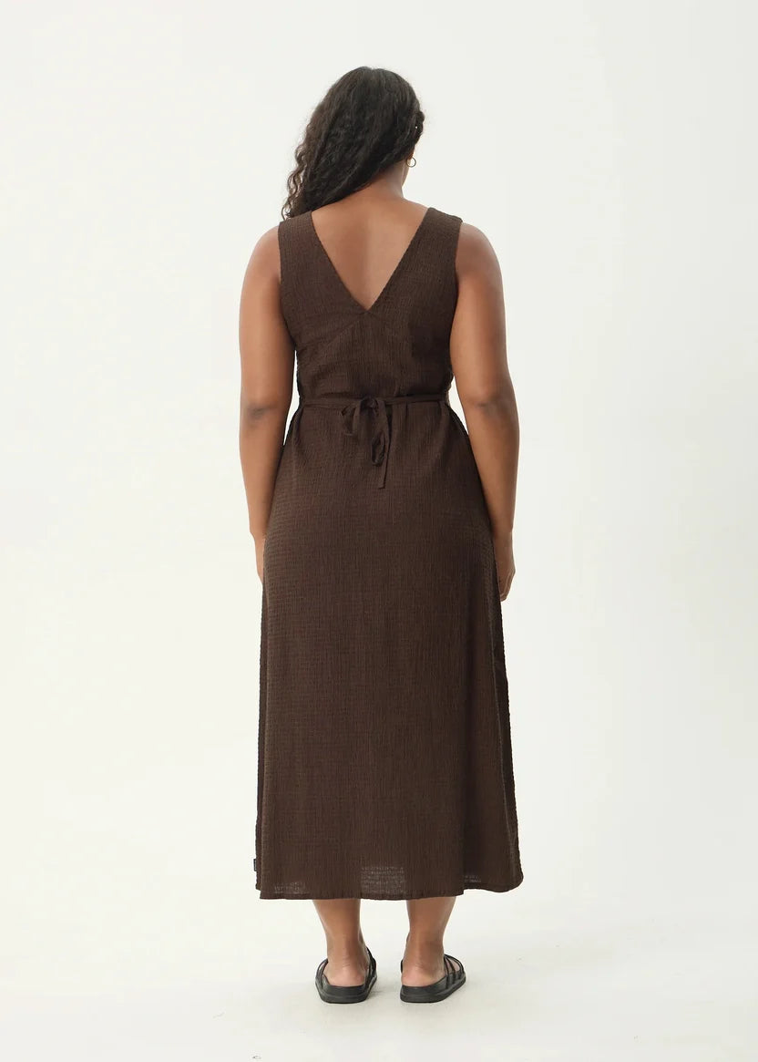 Woman wearing a brown dress from behind on a white background