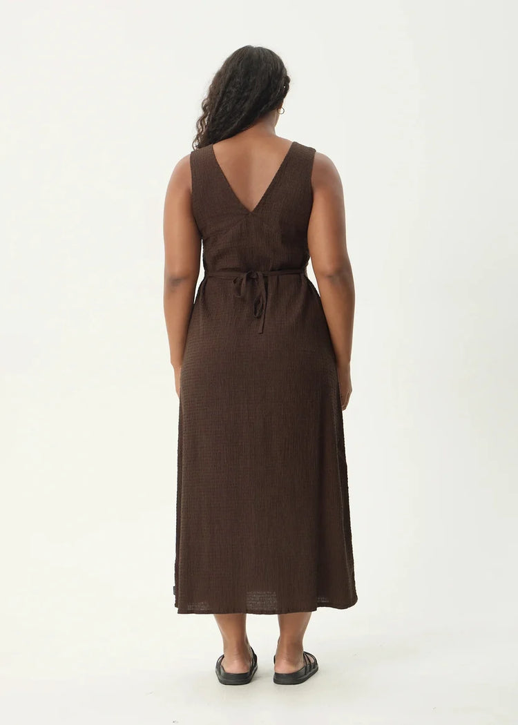 Woman wearing a brown dress from behind on a white background