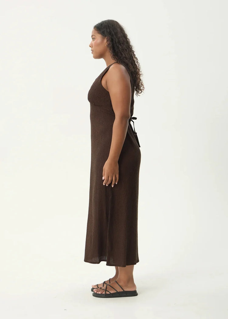 Woman wearing a brown dress standing against a white background