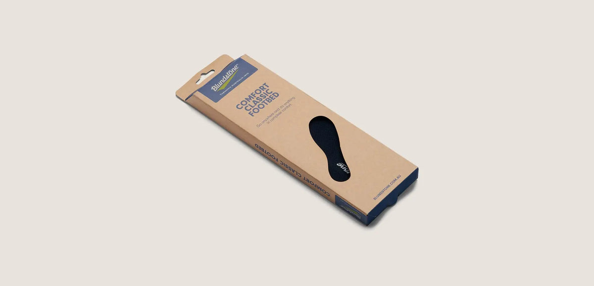 Black shoe insole with yellow accents on a beige background, featuring Blundstone brand.