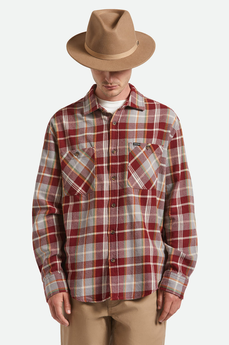 Person wearing a plaid shirt and brown hat on a white background