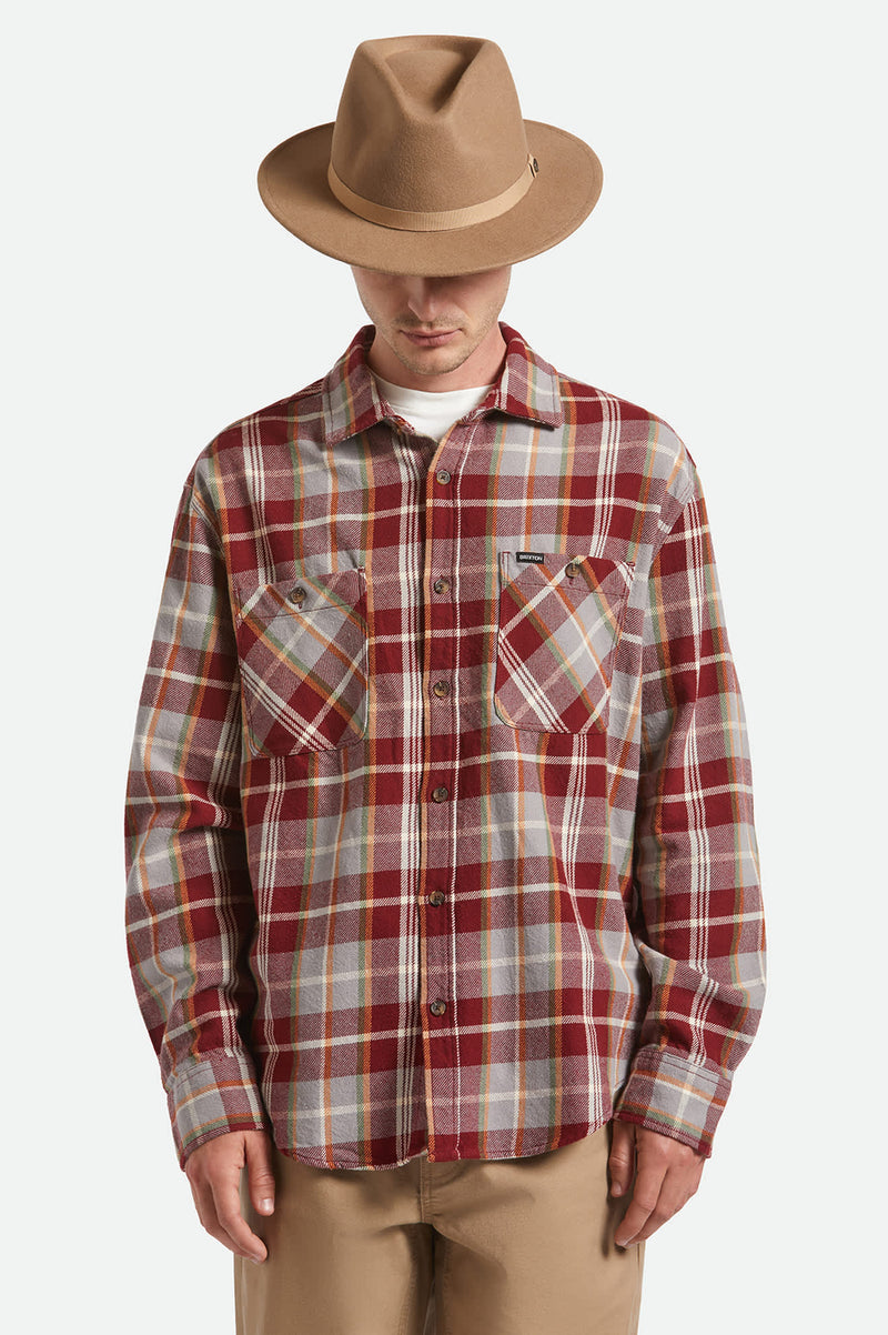 Person wearing a plaid shirt and brown hat on a white background