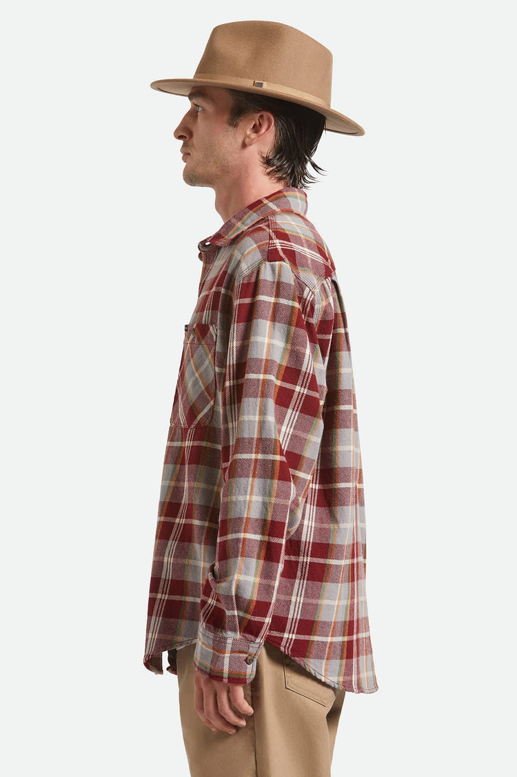 Man wearing a plaid shirt and tan hat on a white background