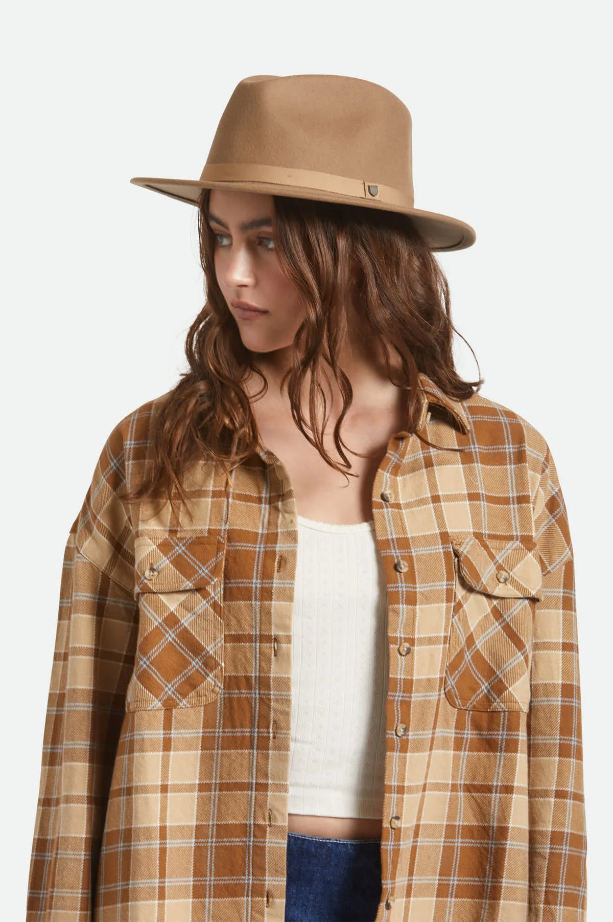 Person wearing a plaid shirt and brown hat on a white background