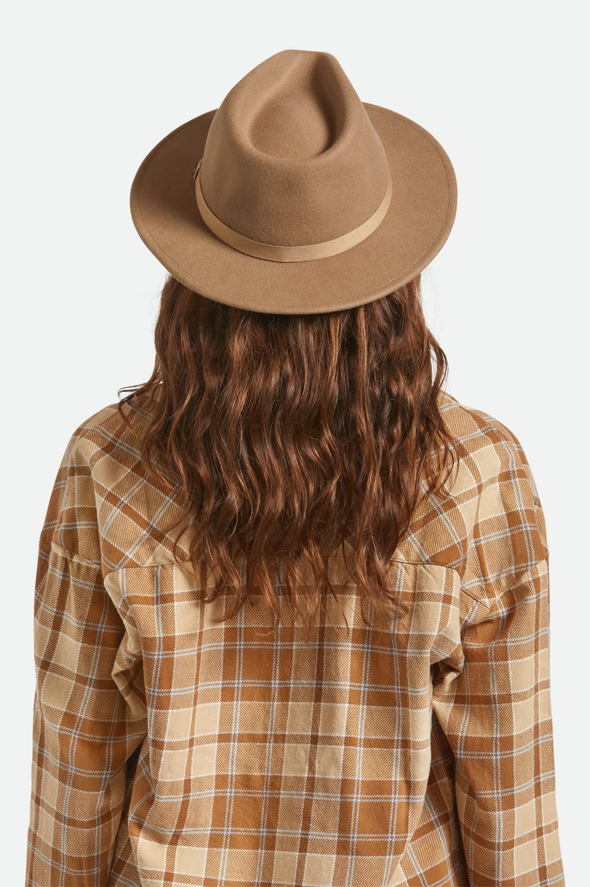 Person wearing a brown fedora and plaid shirt on a white background