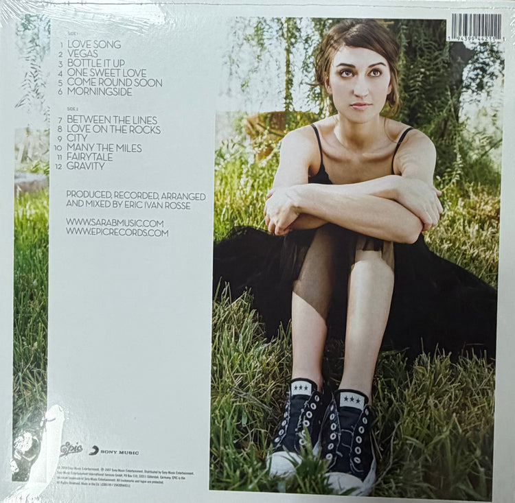 The back cover of a vinyl record sleeve for Sarah Brightman's album 'Between the Lines', sealed in its plastic shrink wrap. The left side features a white background with tracklist text, while the right side displays a color photograph of Sarah Brightman sitting in a grassy outdoor setting.