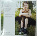 The back cover of a vinyl record sleeve for Sarah Brightman's album 'Between the Lines', sealed in its plastic shrink wrap. The left side features a white background with tracklist text, while the right side displays a color photograph of Sarah Brightman sitting in a grassy outdoor setting.