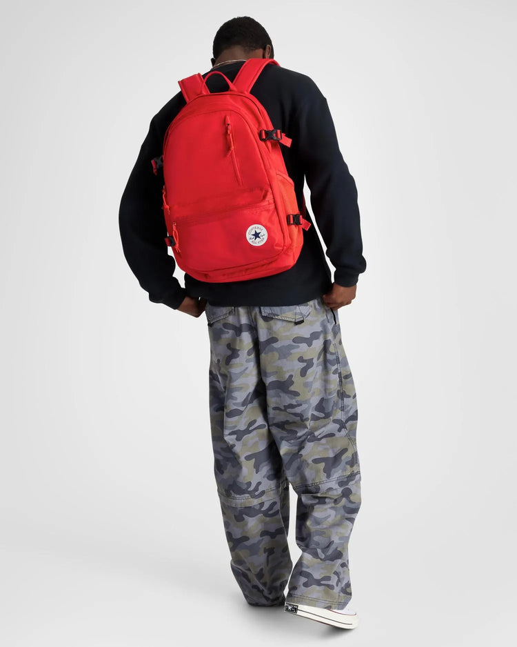 Person wearing a red backpack with a visible brand logo on a white background