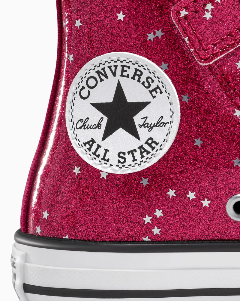 Close-up of a Converse All Star shoe with pink glittery surface and star pattern.