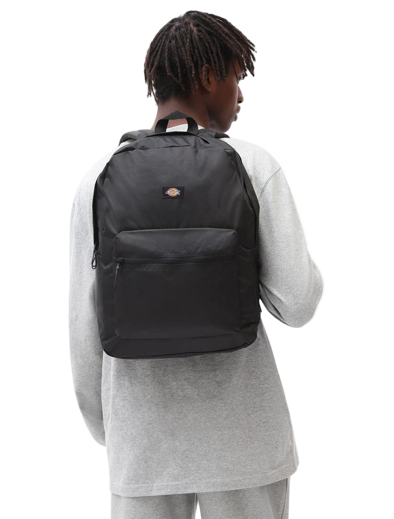 Person wearing a black backpack with a visible brand logo on a white background