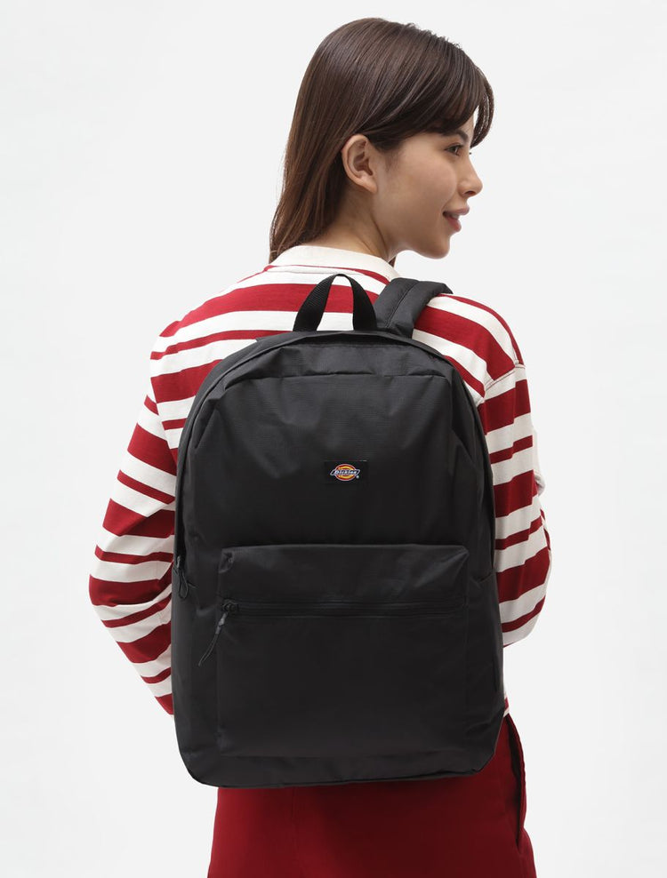 Person wearing a black backpack with a red and white striped shirt on a white background