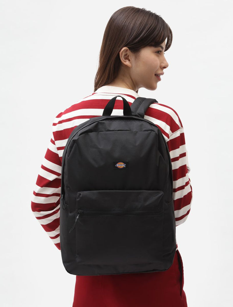 Person wearing a black backpack with a red and white striped shirt on a white background