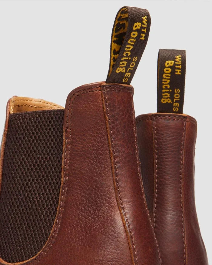Brown leather boots with a visible brand tag on a light gray background