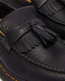 Close-up of Dr Marten Adrian black leather loafers with tassels and orange stitching.