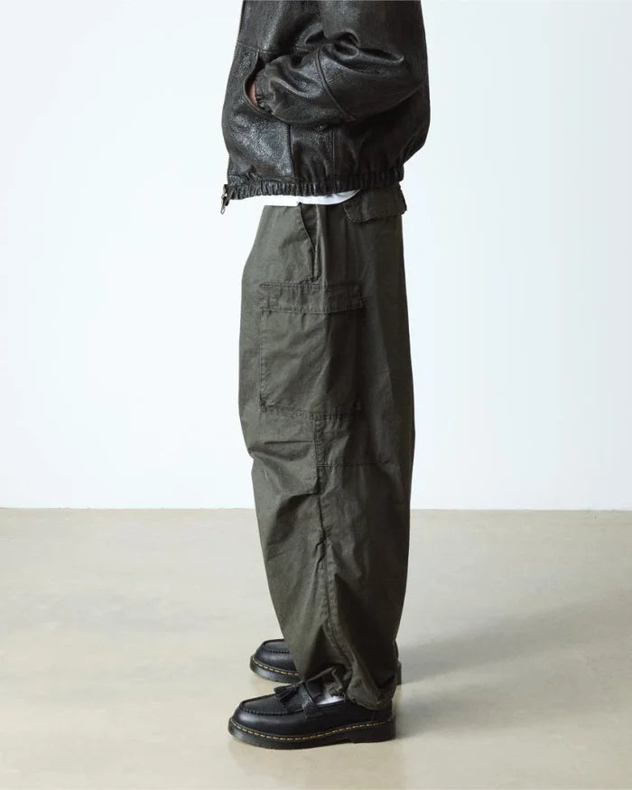 Person wearing dark green cargo pants and Dr Marten Adrian black loafers on a light background