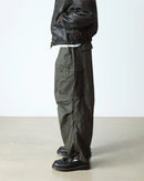 Person wearing dark green cargo pants and Dr Marten Adrian black loafers on a light background