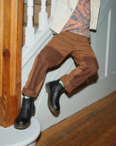 A person jumping on a staircase wearing brown pants and black Dr Martens 2976 softy T boots.