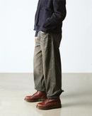 Person wearing dark jacket, gray pants, and brown boots on a white background