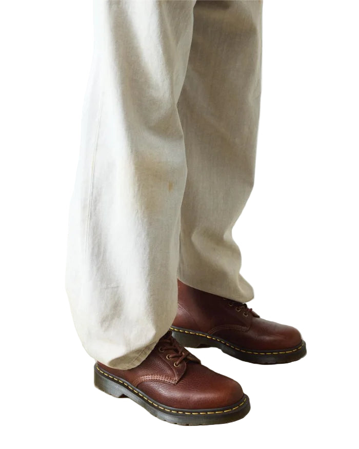 Brown leather shoes worn with beige pants on a light background