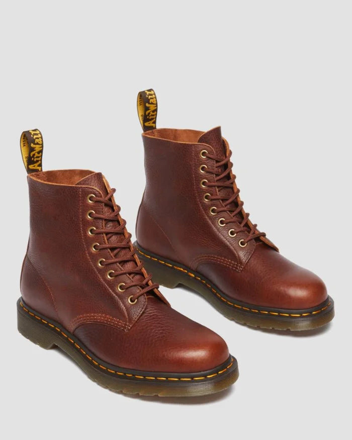 Pair of brown leather boots with yellow stitching on a light gray background