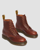 Pair of brown leather boots with yellow stitching on a light gray background