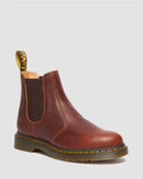 Brown leather Chelsea boot with yellow stitching on a light gray background