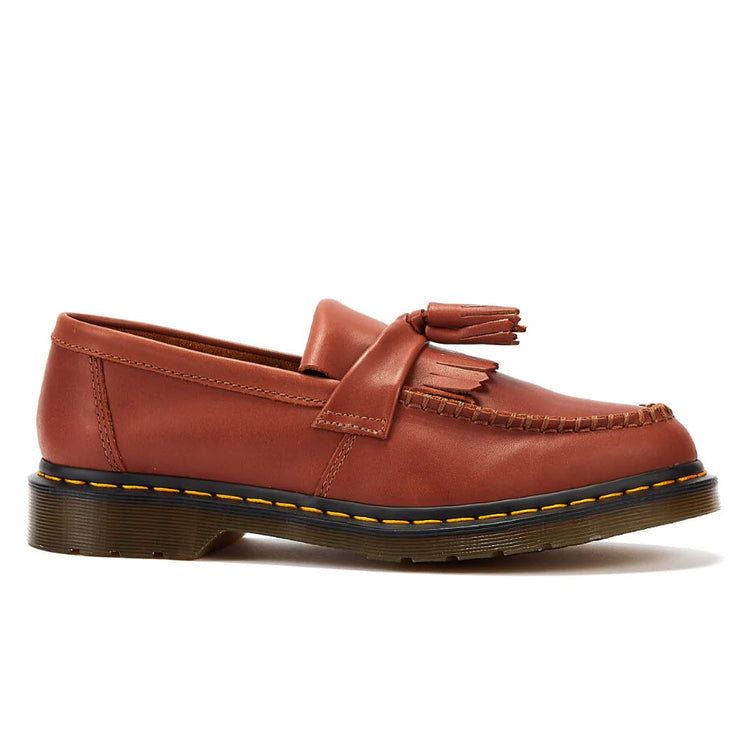 A saddle tan Dr. Martens Adrian tassel loafer with a yellow Goodyear welt stitch and a black rubber sole.