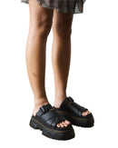 Person wearing black platform sandals on a neutral background