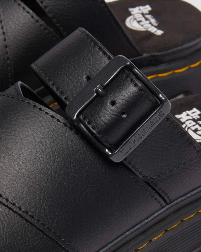 Close-up of a black leather boot with a buckle, featuring the Dr. Martens logo.
